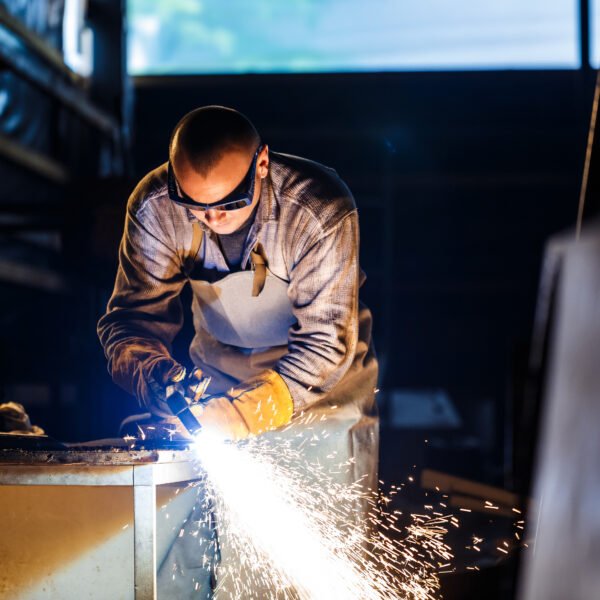 Worker cutting metal with plasma equipment on plant.