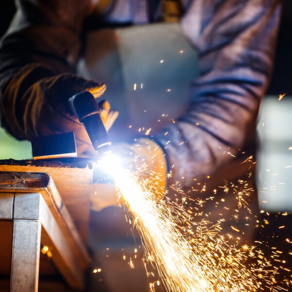 Worker cutting metal with plasma equipment on plant.