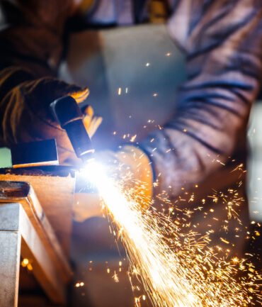 Worker cutting metal with plasma equipment on plant.