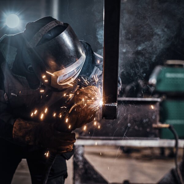Man is working at metal factory, he is welding a piece of rail using special tools.